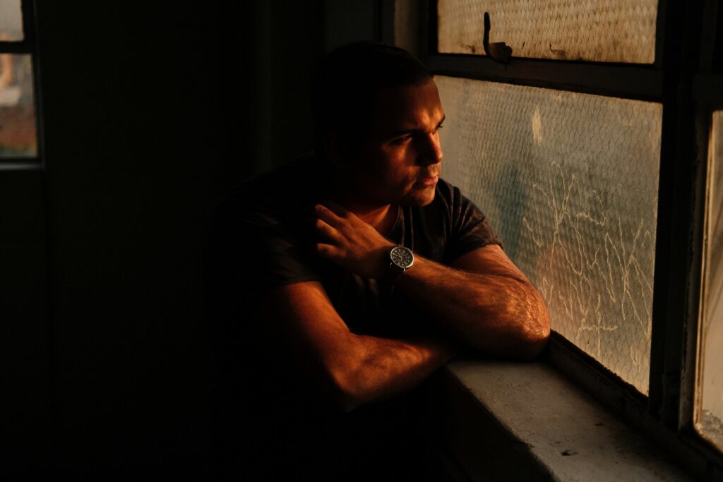 man staring outside rainy window