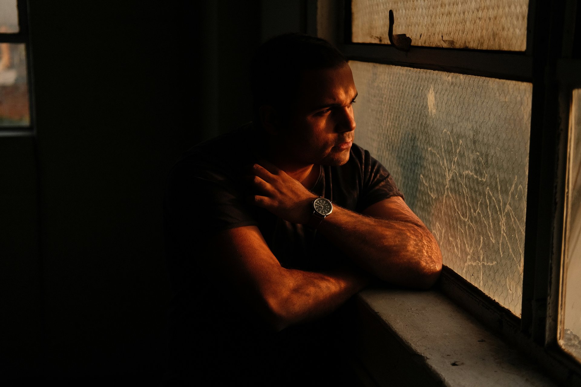 man staring outside rainy window