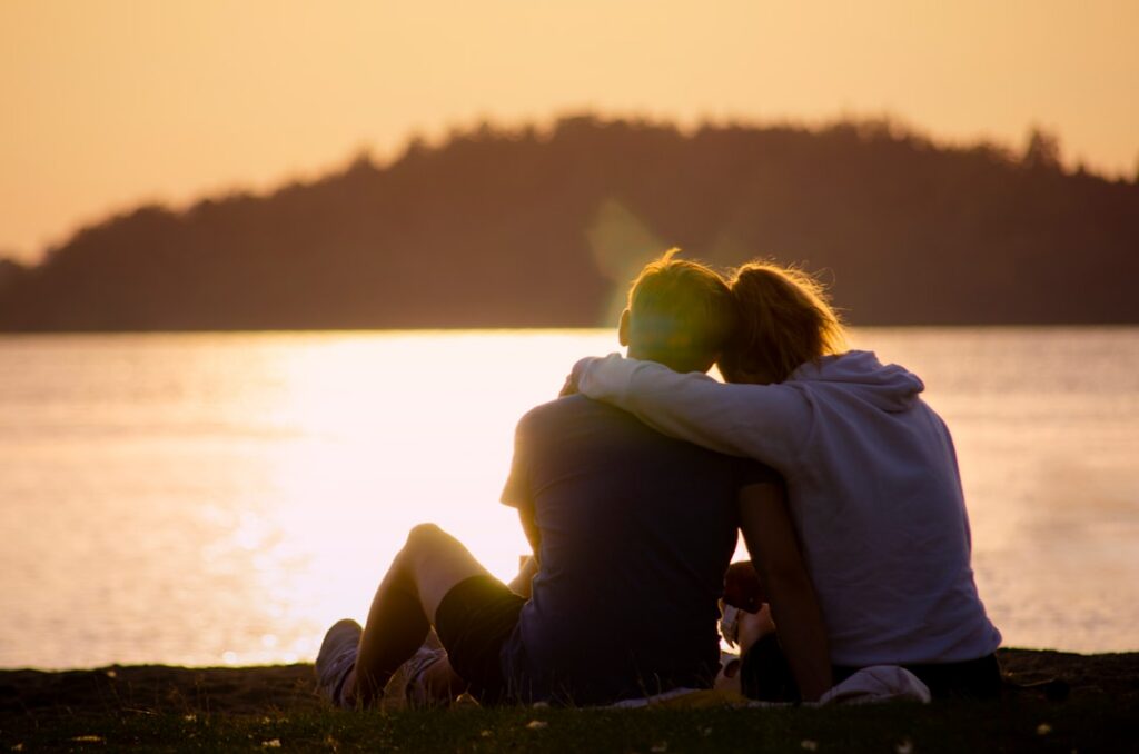 a couple hugging looking into a lake during sunset